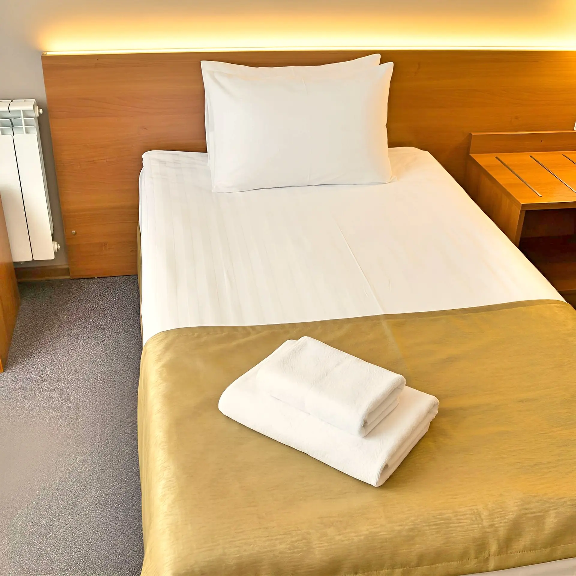 Elegant premium hotel room interior 'Standard' category in Saratov, king size bed with high-quality white linens, wooden furniture, warm evening lighting, soft textures, minimalist decor, 8k professional hospitality photography, cozy atmosphere.
